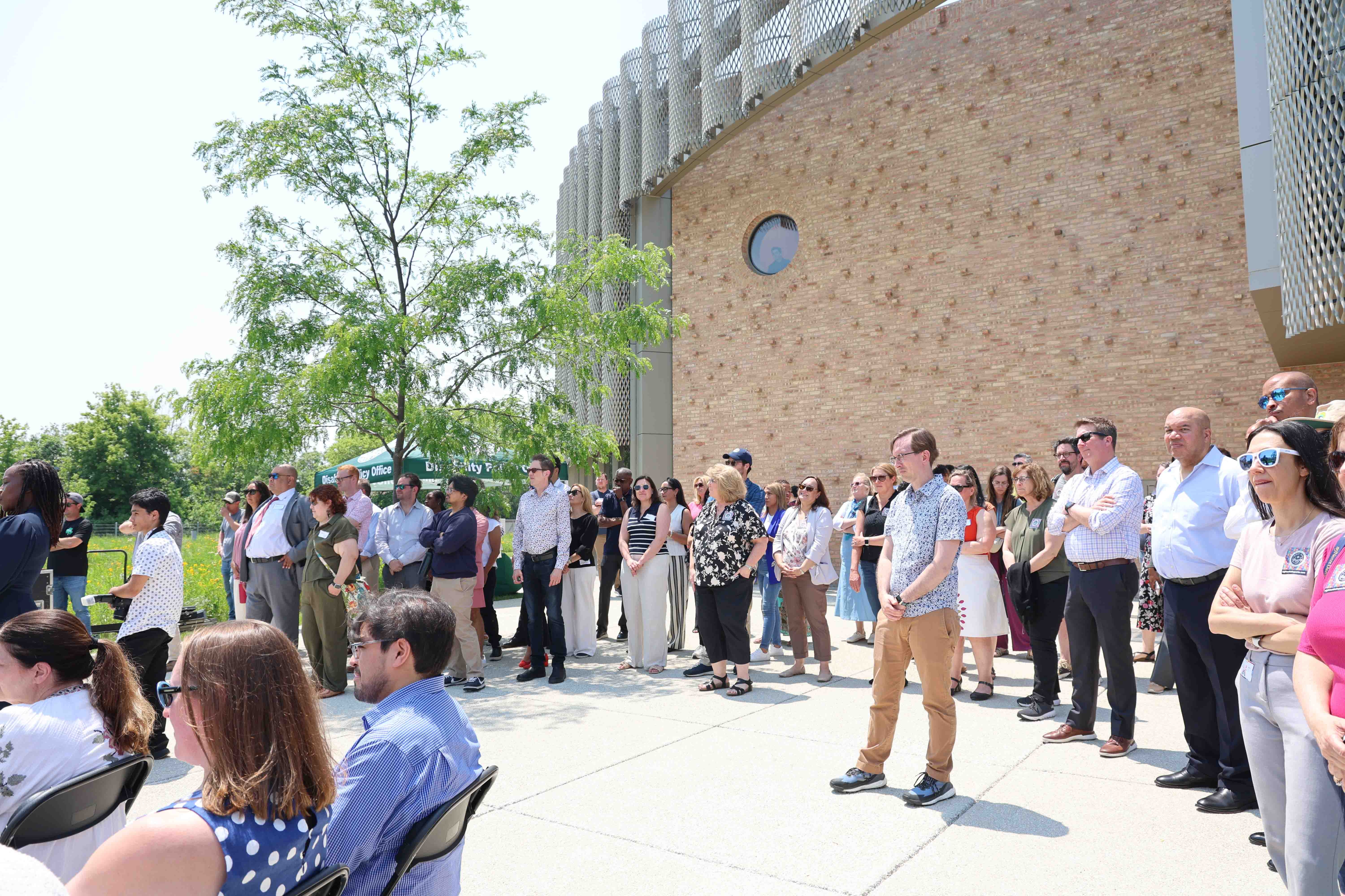 Crowd gathers outside a modern brick building with a decorative metal facade.